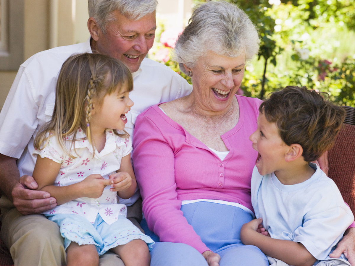 grandparents sat on a sofa laughing with grandchildren HtcAiHRri PMNW