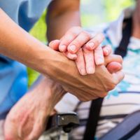 senior and caregiver holding hands