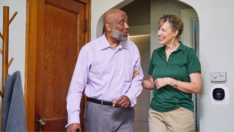 Home Instead caregiver supports senior client walking through home in Tipp City, OH